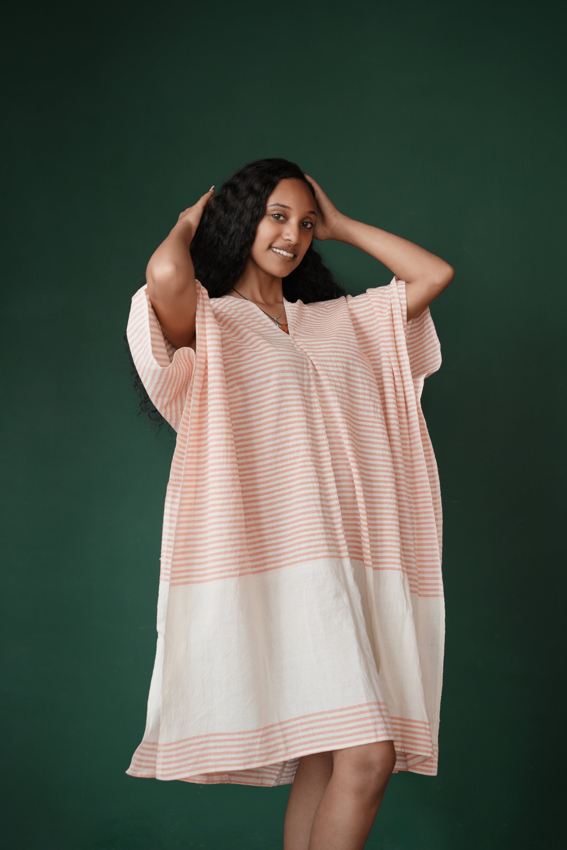 Ari kaftan in salmon facing forward on geen background