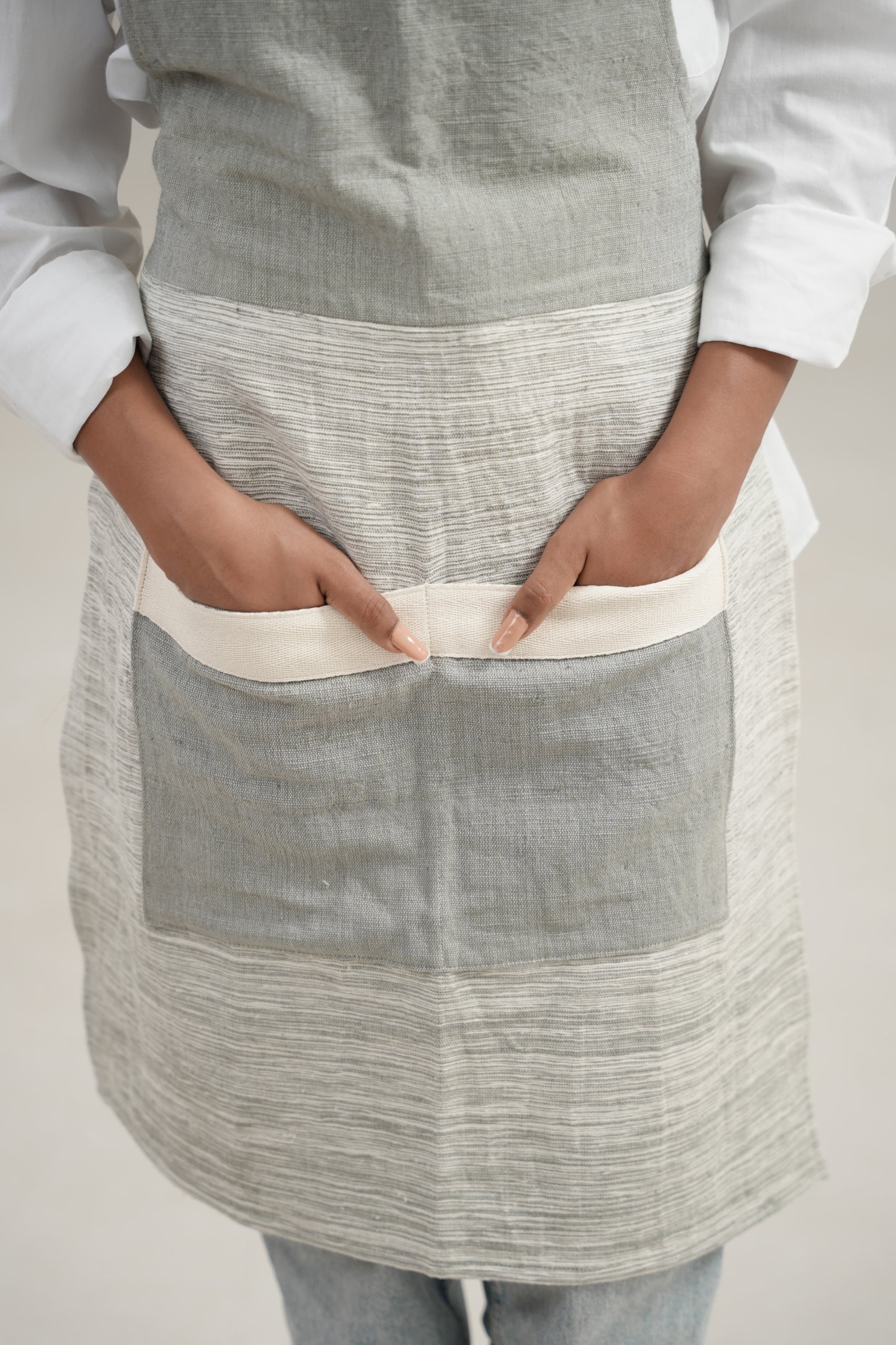 Close up on pockets of Apron in grey on ethiopian model with white background