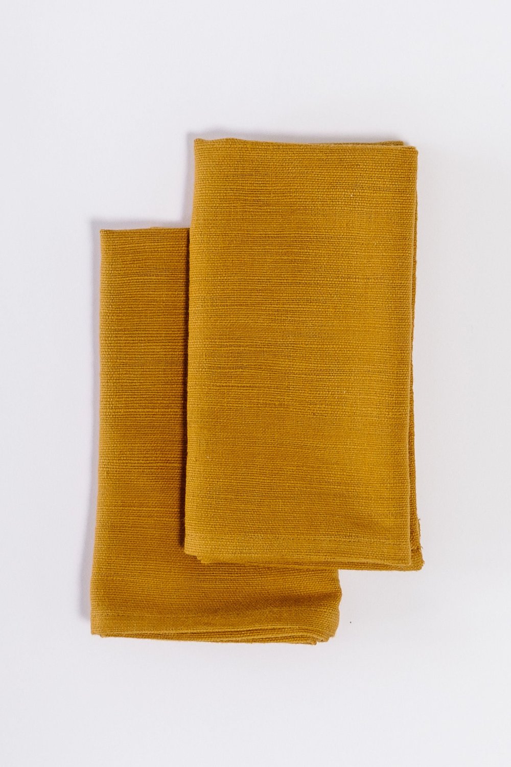 Two Semien cocktail napkins in bronze folded on white background