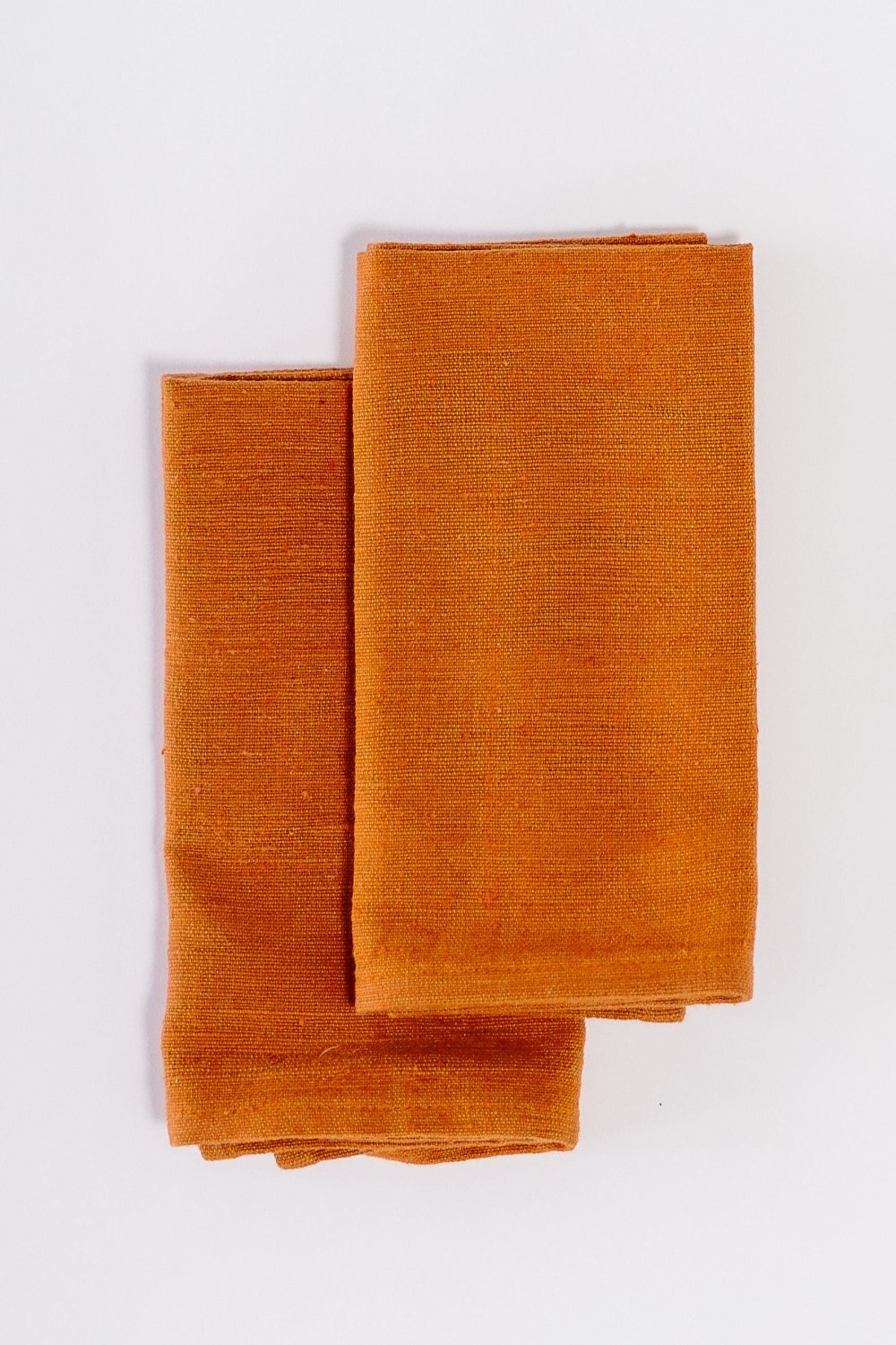 Two Semien cocktail napkins in copper folded on white background