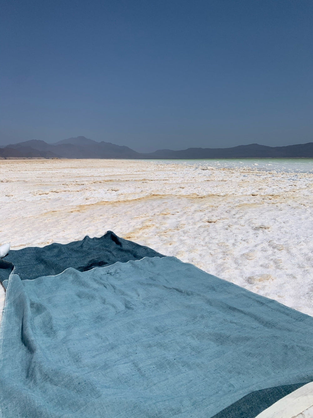 Abay steel blue towel on a salt flat with mountains in the background