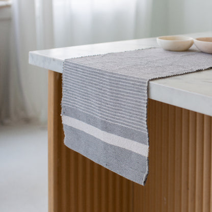 Adwa table runner on a white marble table with a blurred background