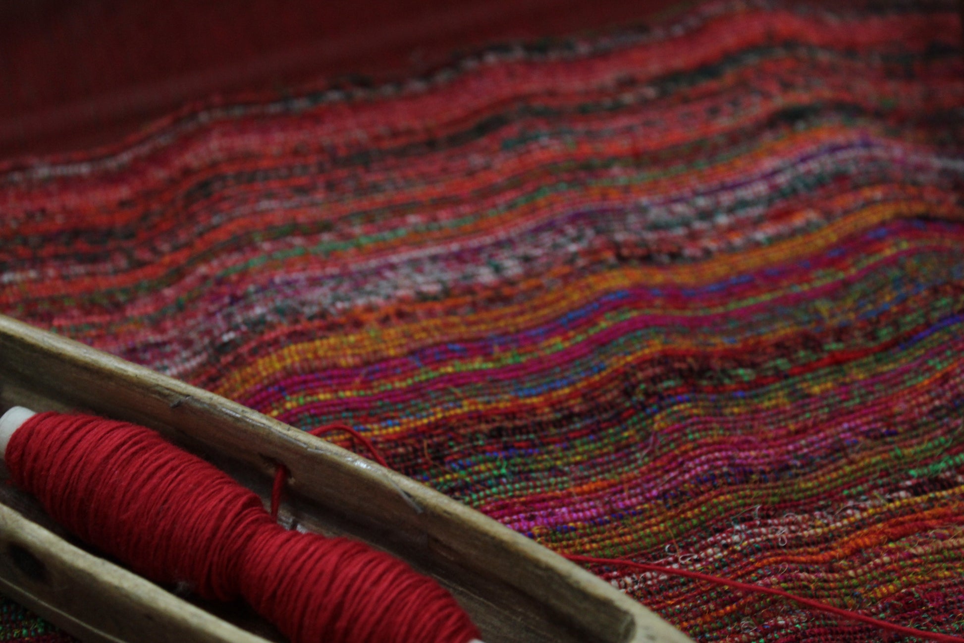Close-up of harar fabric with a spool of red thread on a wooden surface.