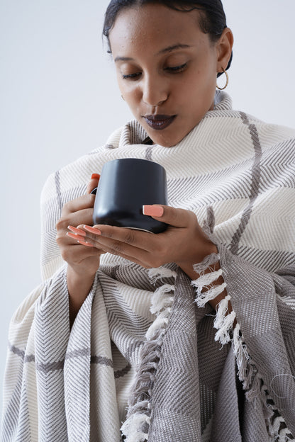 Ethiopian model holding black mug wrapped in ayele blanket