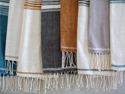 Collection of genalé towels with fringes on a neutral background
