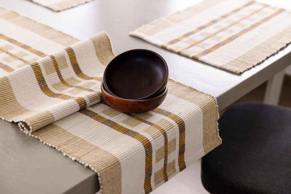 Gonder table runner and placemat in bronze on a table with wooden bowls