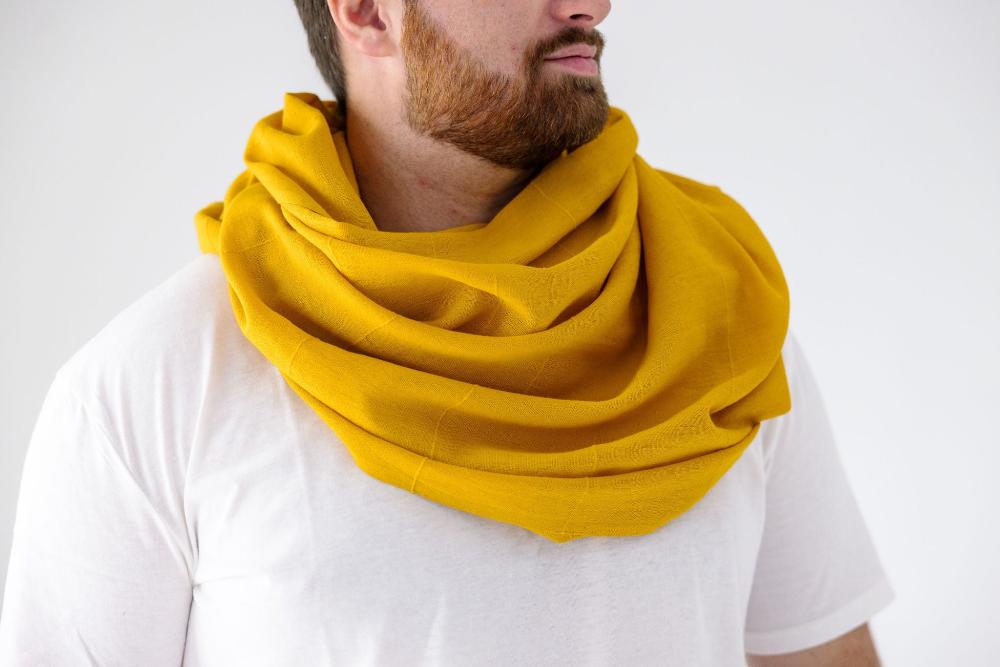 Male model wearing a gold Maraki shawl around his neck.