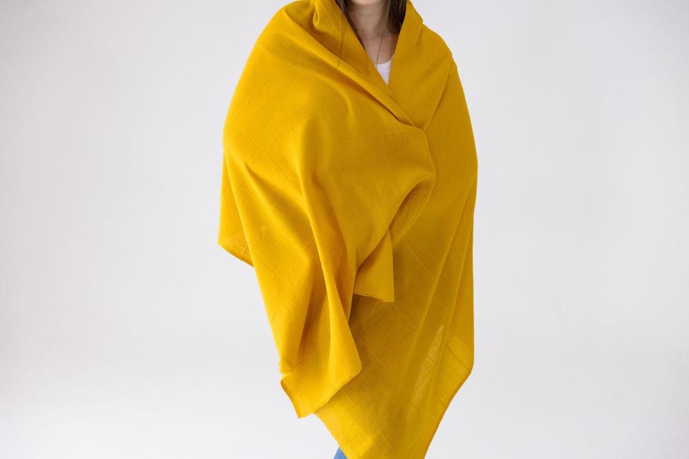 Female model wearing the Maraki shawl in gold