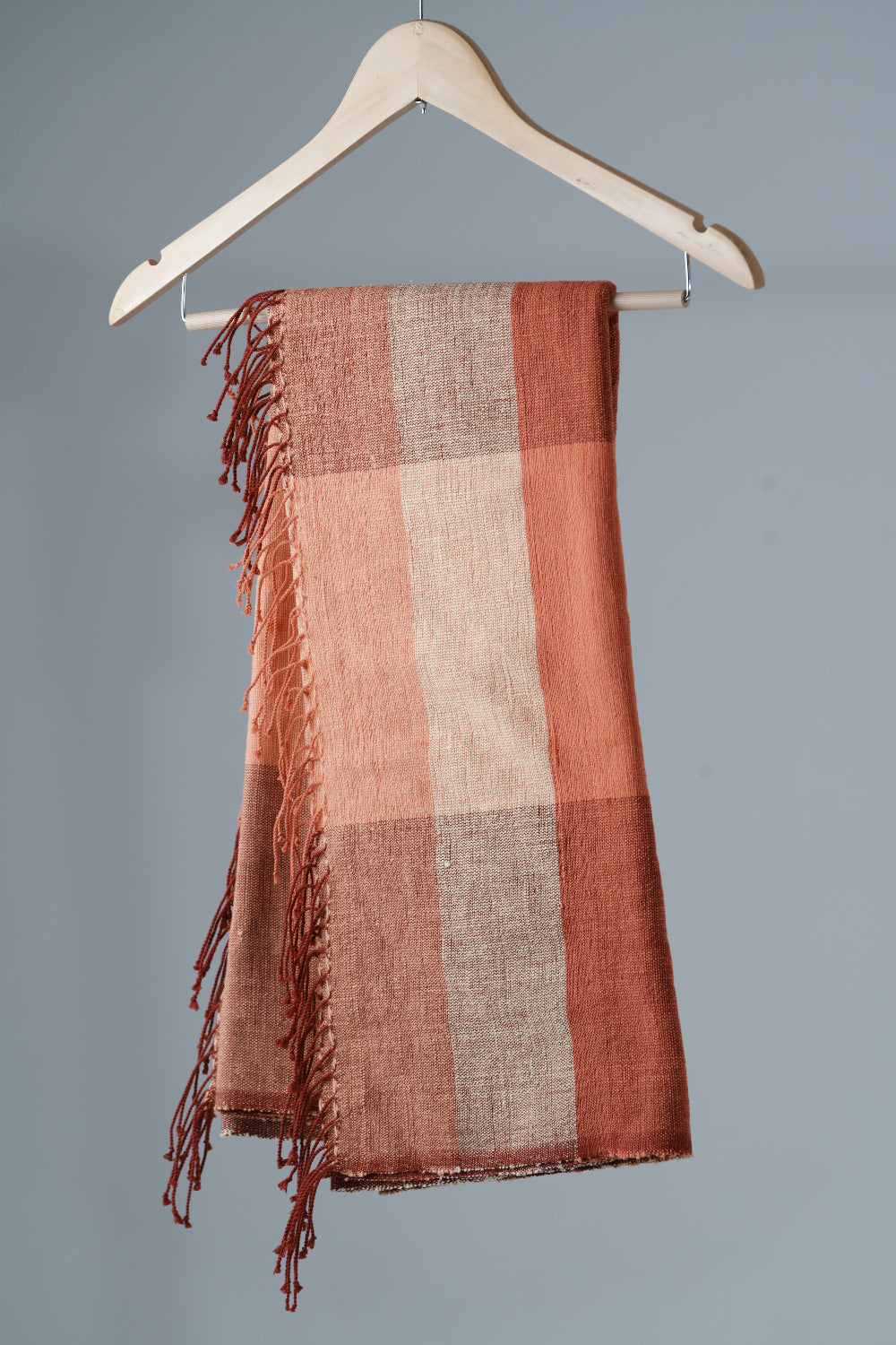 Mareb towel in salmon on a hanger against a gray background