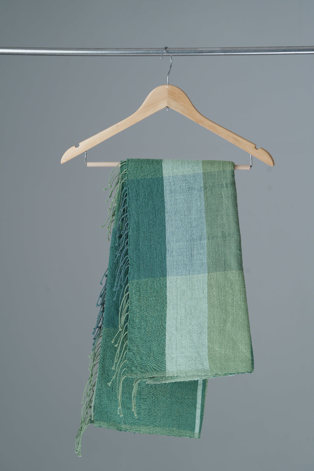Mareb towel in teal on a hanger against a gray background
