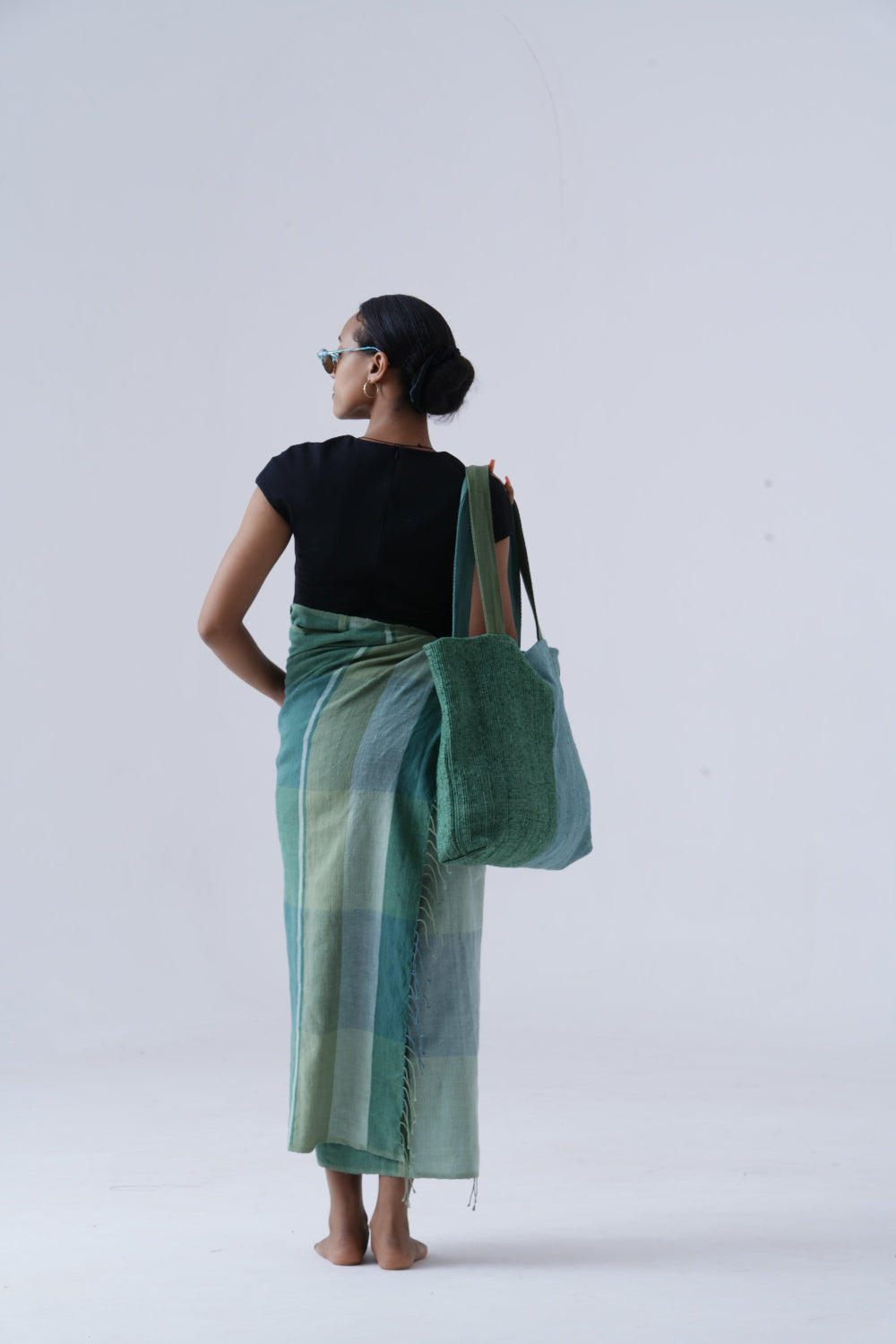 Model holding borsa tote on shoulder with mareb towel wrapped around her waist