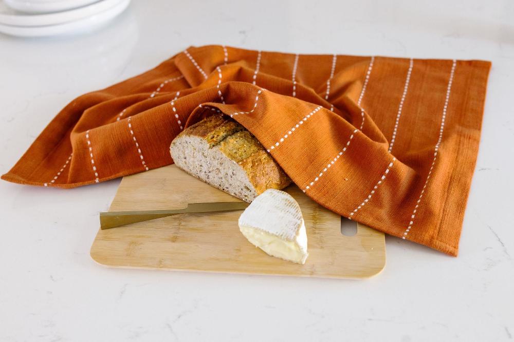 Rift Valley tea towel in copper on kitchen counter with bread and cheese