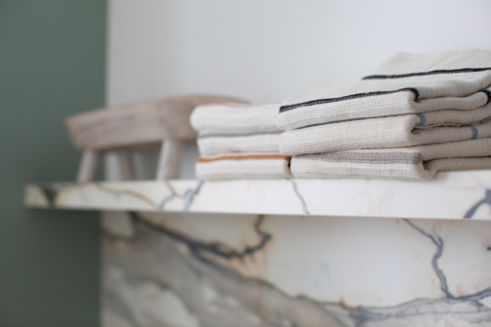 Stack of folded wari hand towels on a marble shelf with a blurred background