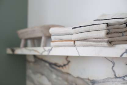 Stack of folded wari hand towels on a marble shelf with a blurred background