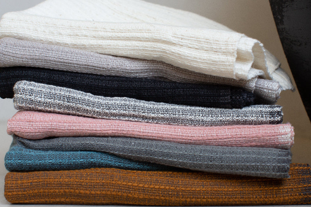 Stack of folded zarima bath towels in various colors on a neutral background