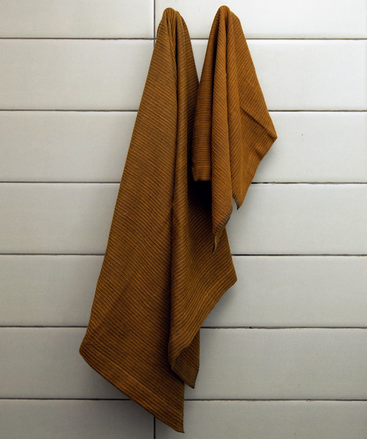 Handwoven bath towel in bronze, displayed in a bathroom setting.