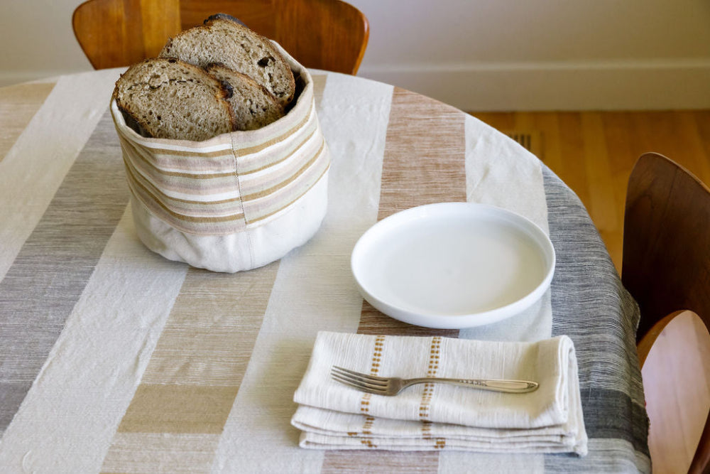 dabo basket with bread slices on tablecloth with folded chamo napkin in bronze