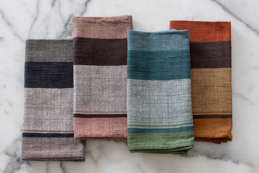 Four dalol napkins in different colors on a marble surface