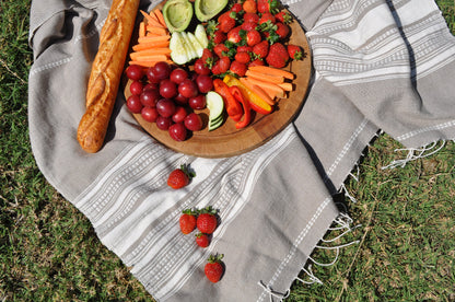 genalé towel in stone ivory outdoors on grass with wooden plate with fruits and vegetables