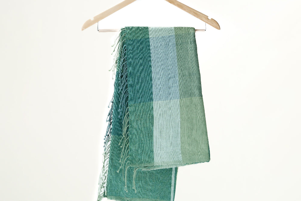 mareb towel in teal hanging against white background