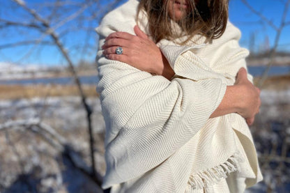 Mechot throw blanket in ivory wrapped around female model in nature