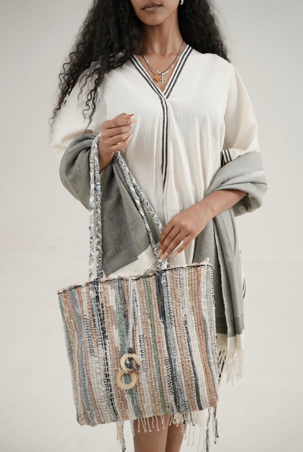 model wearing petra kaftan with abay towel and holding fasika bag 