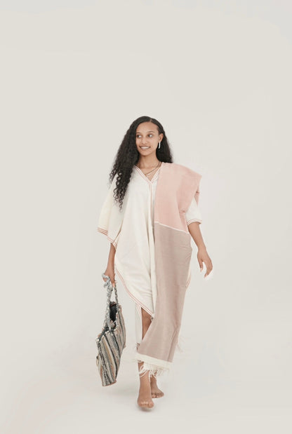 model wearing petra kaftan with abay towel in blush holding fasika bag