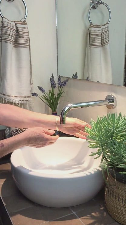 Lady using genaleé hand towel in bronze to dry her hands