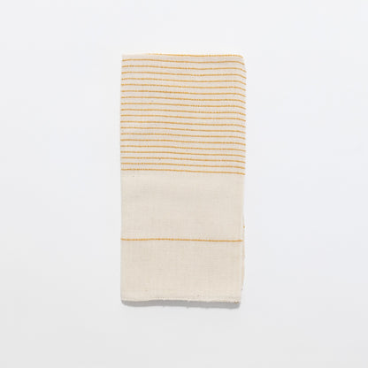 Roha napkin in gold flat lay on a white background