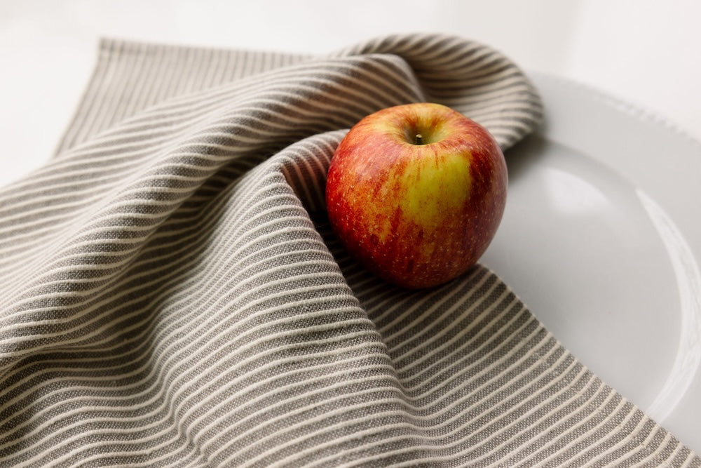 turkana tea towel in stone with an apple on white table